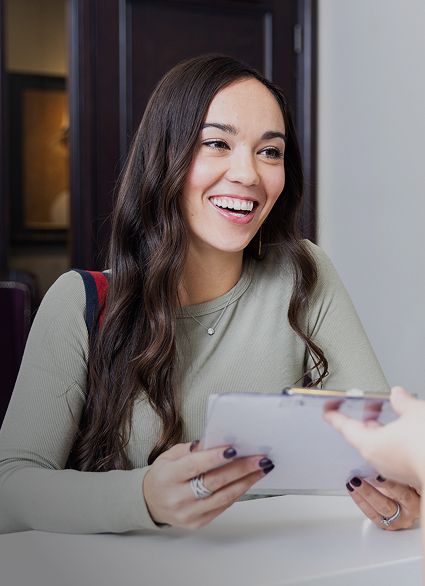 Smiling woman receiving a document at a table.